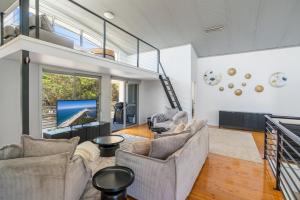 een woonkamer met twee banken en een flatscreen-tv bij Seven Miles Beach Escape in Shoalhaven Heads