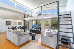 een woonkamer met twee banken en een tv bij Seven Miles Beach Escape in Shoalhaven Heads