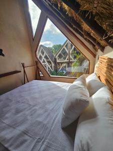 ein Bett in einem Zimmer mit einem großen Fenster in der Unterkunft Kaaj Ndomi in Bacalar