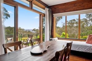 comedor con mesa de madera y ventanas grandes en Banksia Tops, en Leura