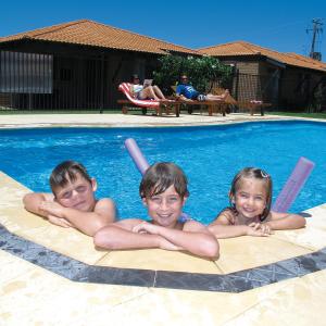 tres chicos jóvenes tirados en una piscina en Geraldton's Ocean West Holiday Units & Short Stay Accommodation, en Geraldton