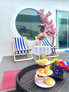 a table with plates of food and two chairs at Sea Fan Cha-am Pool Villa in Ban Bo Prakhon