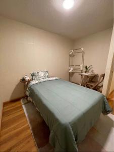 a bedroom with a bed with a green blanket at Acogedora habitación in Lima