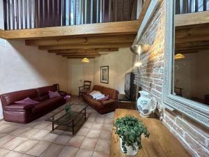a living room with leather furniture and a brick wall at Gite de lescurade in Escource