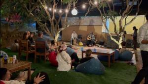 Eine Gruppe von Menschen sitzt auf dem Rasen und schaut sich eine Präsentation an. in der Unterkunft 12 Monks - Backpacker Resort in Arambol