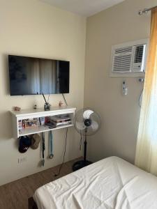 een slaapkamer met een bed, een tv en een ventilator bij Stanford Suites 1 in Silang
