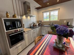 een keuken met een tafel met een vaas met paarse bloemen bij Le gite grues cendrees in Arjuzanx
