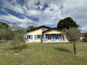 een geel huis met blauwe luiken in een veld bij Le gite grues cendrees in Arjuzanx