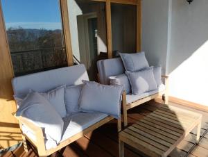 eine Veranda mit 2 Stühlen und ein Sofa mit Kissen in der Unterkunft Private secluded villa for 20 guests on large private estate - Cairo Montenotte - Tenniscourt - Savone in Cairo Montenotte