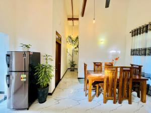 a dining room with a table and chairs and a refrigerator at Green Hill Villa Thalpe in Talpe