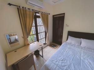 a bedroom with a bed and a desk and a window at Avana Guesthouse in Kalasan +2 photos