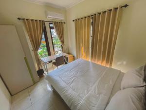 a bedroom with a bed and a desk and a window at Avana Guesthouse in Kalasan