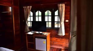 ein Schlafzimmer mit einem Fernseher auf einem Tisch vor einem Fenster in der Unterkunft Little Home Beach in Ban Khok Rak