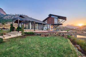 a house on a hill with the sunset in the background at SaffronStays Villa Reya in Trimbak