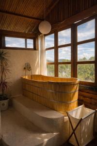 eine große Holzbadewanne in einem Zimmer mit Fenstern in der Unterkunft Chu Mansion - Chill & Grill and Pickeball in Da Thien