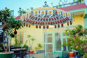 a patio with tables and chairs in front of a house at The Gulmohar Villa in Tājganj