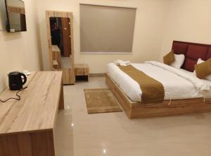 a bedroom with a bed and a wooden desk at Hotel SJ corporate in Bhubaneshwar