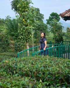 een vrouw die naast een groen hek staat bij Sylora Meadows Private Pool Villa ,Vagamon in Pīrmed