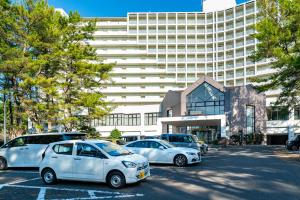twee witte auto's geparkeerd op een parkeerplaats voor een gebouw bij Seagaia Forest Condominiums in Miyazaki