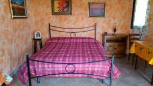 a bedroom with a bed with a pink comforter at Appartamento Il Salice in Casa Minnina