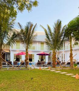 a resort with palm trees in front of a building at White Elephant Hostel in Luang Prabang