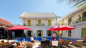 a group of people sitting around a swimming pool with umbrellas at White Elephant Hostel in Luang Prabang