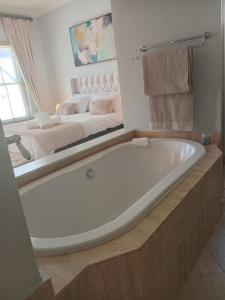een wit bad in een badkamer met een spiegel bij L'Ermitage Villa Francois in Franschhoek