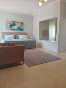 een slaapkamer met een bed, een bank en een spiegel bij L'Ermitage Villa Francois in Franschhoek +6 foto's