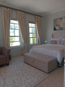 een slaapkamer met een groot bed en een bank bij L'Ermitage Villa Francois in Franschhoek