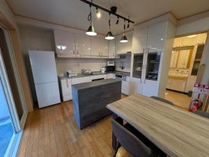 eine Küche mit weißen Geräten und einem Holztisch mit Stühlen in der Unterkunft A214Fujiyama Stay Sengen West in Fujinomiya