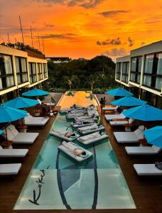 een groep mensen die op ligstoelen in een zwembad met parasols liggen bij Awwa Boutique Hotel in Canggu