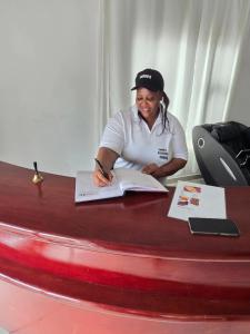 een vrouw aan een bureau die een document ondertekent bij Shado's residence self catering cotages in Serowe