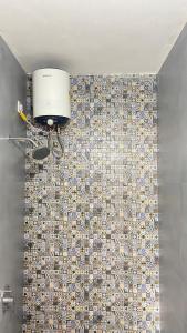 ein Badezimmer mit einer Mosaikfliesenwand und einer Beleuchtung in der Unterkunft Go-Kul Home Stay in Kolhapur