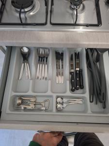 un cassetto pieno di utensili sotto una stufa di Sant Antioco Yellow Apartment with 2 Way Air Con a SantʼAntìoco