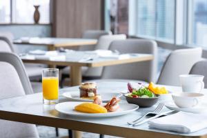 a table with plates of food and a glass of orange juice at The Prince Park Tower Tokyo - Preferred Hotels & Resorts, LVX Collection in Tokyo
