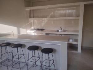 a kitchen with three bar stools and a sink at Apartamentos Turiksa in Acapulco +3 photos