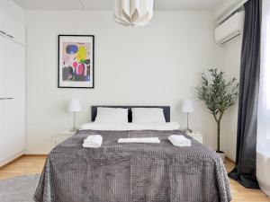 een witte slaapkamer met een bed met een grijze deken bij Modern Airport Apartment in Vantaa