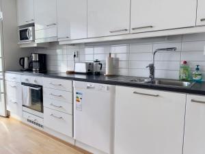 een keuken met witte kasten en een spoelbak bij Modern Airport Apartment in Vantaa +6 foto's