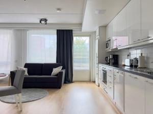 een woonkamer met een bank en een keuken bij Modern Airport Apartment in Vantaa