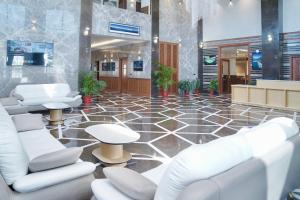een lobby met witte stoelen en tafels op een tegelvloer bij Le OVAL Hotel & Resorts in Nakraunda