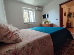 a bedroom with a bed with a blue blanket and a window at La Casa del Fungo in Montalto Uffugo