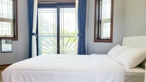 ein Schlafzimmer mit einem weißen Bett und einem Fenster in der Unterkunft Samcheok Duelkkot Pension in Samcheok