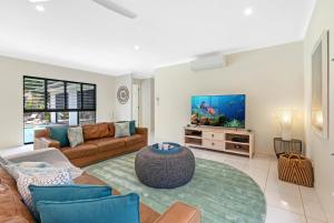 a living room with a couch and a tv at Belle Escapes Sandcastles in Palm Cove