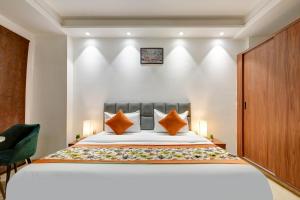 a bedroom with a large bed with orange pillows at Qotel Comfort Ashok Vihar in New Delhi
