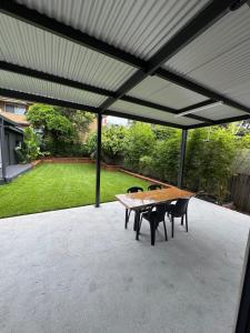 eine Terrasse mit einem Holztisch und Stühlen unter einer Markise in der Unterkunft HOME away from HOME in Sydney