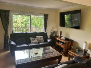 a living room with a black leather couch and a table at Beachy Sounds House in Carters Beach