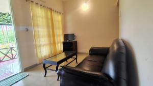 a living room with a leather couch and a coffee table at Elephant Pass Ayurveda & Yoga Retreat in Malayāttūr +20 photos