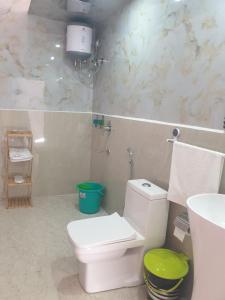 ein Badezimmer mit weißer Toilette und Waschbecken in der Unterkunft D'Resort in Masuri