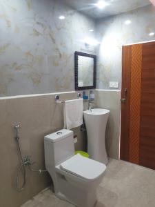 ein Badezimmer mit weißer Toilette und Waschbecken in der Unterkunft D'Resort in Masuri