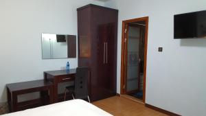 Schlafzimmer mit einem Schreibtisch, einem Bett und einem Spiegel in der Unterkunft White City Inn in Gaborone